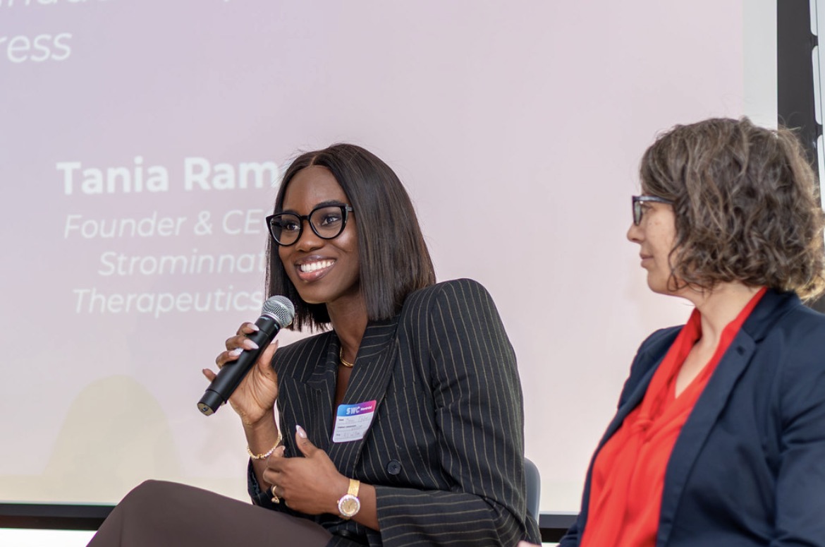 Joan Ofulue speaking on the Impostor to Impact panel at the STEM Women Congress in Montreal, holding a microphone.